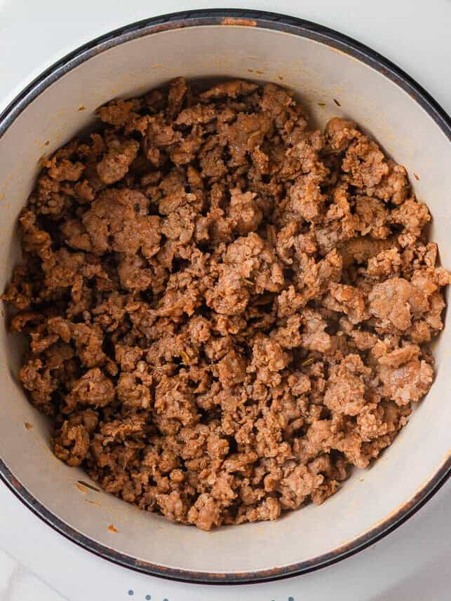 This creamy sausage potato soup is made in one pot with Italian sausage, tender potatoes, and a cheesy broth, it's a cozy way to satisfy the whole family! Browning sausage in Dutch oven.