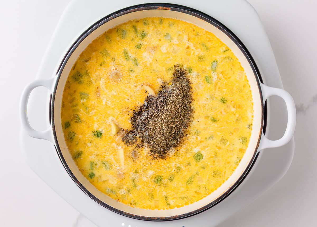 This creamy sausage potato soup is made in one pot with Italian sausage, tender potatoes, and a cheesy broth, it's a cozy way to satisfy the whole family! Adding cheese and sausage to a large Dutch oven for sausage potaot soup.