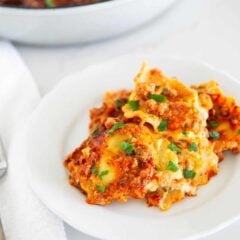 Million dollar ravioli casserole on a white plate garnish with parsley.