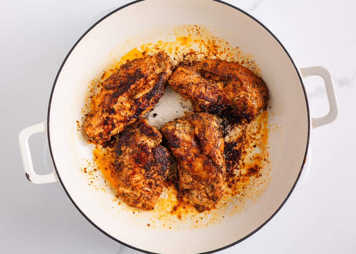 This blackened chicken Alfredo is an easy weeknight dinner that combines creamy Alfredo sauce with blackened chicken for a Southern twist on an Italian classic! Seasoned chicken breasts searing in a white skillet until blackened and golden brown.