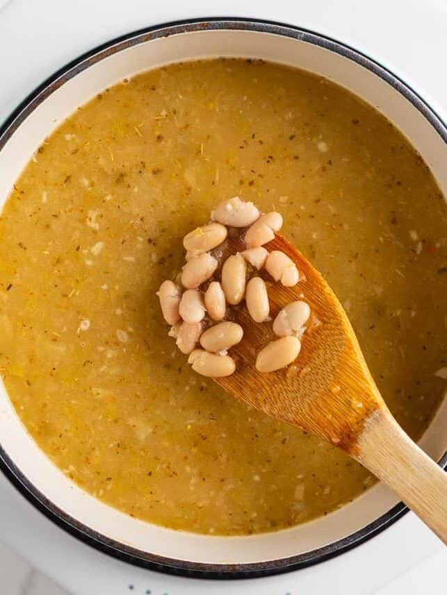 Stirring white beans into the simmering broth for white chicken chili.