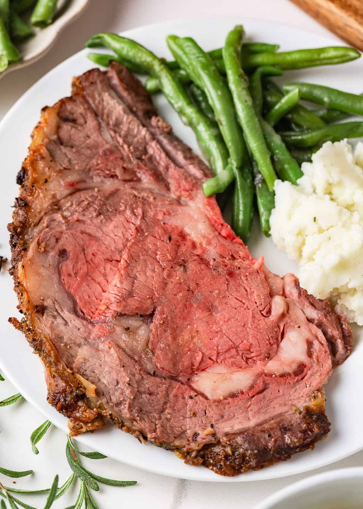 Juicy, flavorful, and perfectly cooked prime rib made right at home! With a beautifully seasoned crust and bone-in presentation, it's festive for the holidays or special occasions. A tender, juicy slice of prime rib roast served with mashed potatoes and green beans.