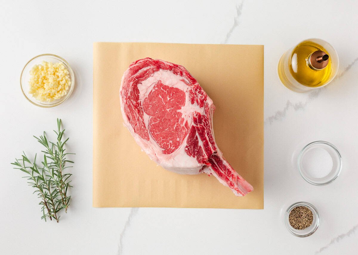 Juicy, flavorful, and perfectly cooked prime rib made right at home! With a beautifully seasoned crust and bone-in presentation, it's festive for the holidays or special occasions. Uncooked prime rib roast on butcher paper with garlic, rosemary, olive oil, salt, and pepper.