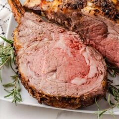Juicy prime rib roast cooked perfectly, sliced and ready to serve with rosemary garnish.