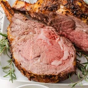 Garlic herb prime rib recipe sliced on a platter showing juicy, tender and melt-in-your mouth roast.