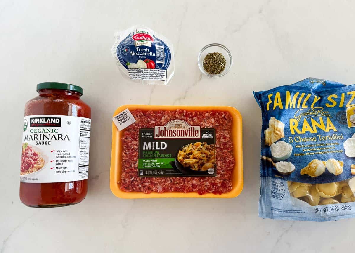 Ingredients for baked tortellini including marinara sauce, Italian sausage, mozzarella cheese, Italian seasoning, and cheese tortellini.
