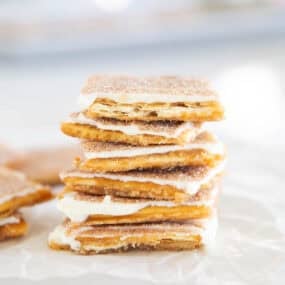 Stack of churro saltine toffee squares layered with caramel, white chocolate, and cinnamon sugar.