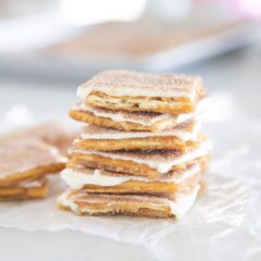 Churro saltine toffee pieces piled on parchment with more pieces in the background.