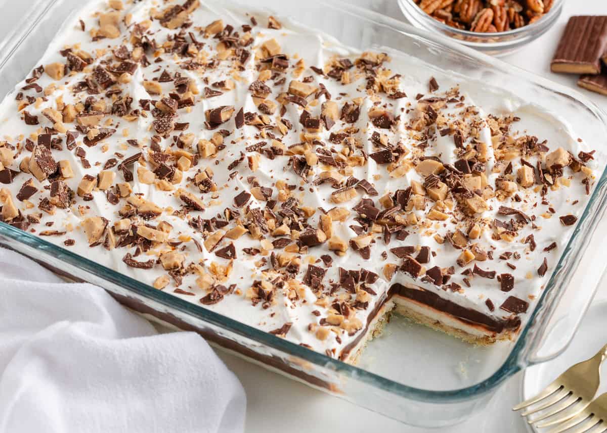 Finished chocolate delight dessert topped with whipped cream and chopped toffee pieces in a glass baking dish.