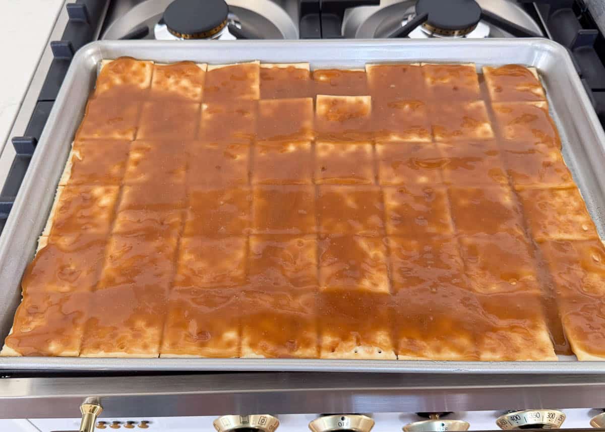 Caramel coating the saltines for churro toffee candy.