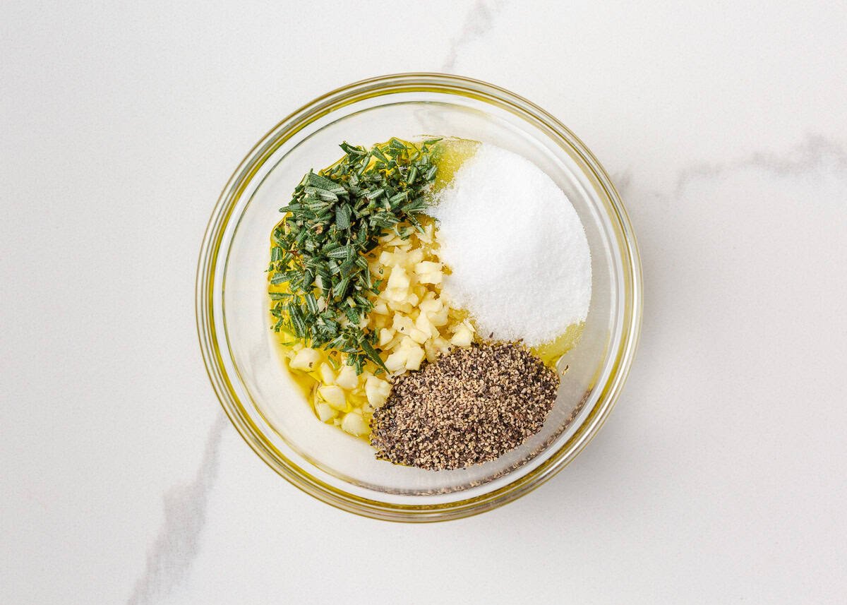 Juicy, flavorful, and perfectly cooked prime rib made right at home! With a beautifully seasoned crust and bone-in presentation, it's festive for the holidays or special occasions. Bowl of prime rib rub with garlic, rosemary, olive oil, salt, and pepper.