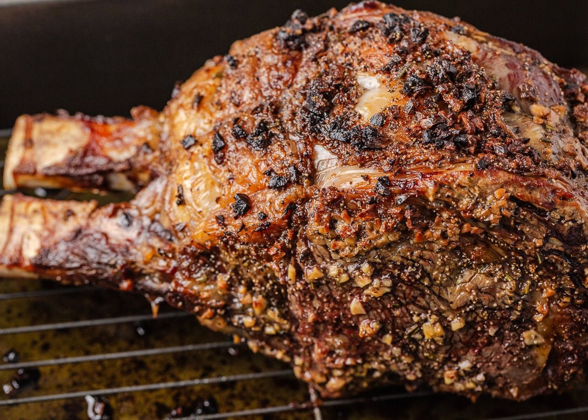 Juicy, flavorful, and perfectly cooked prime rib made right at home! With a beautifully seasoned crust and bone-in presentation, it's festive for the holidays or special occasions. Garlic herb prime rib resting in a roasting pan after cooking.