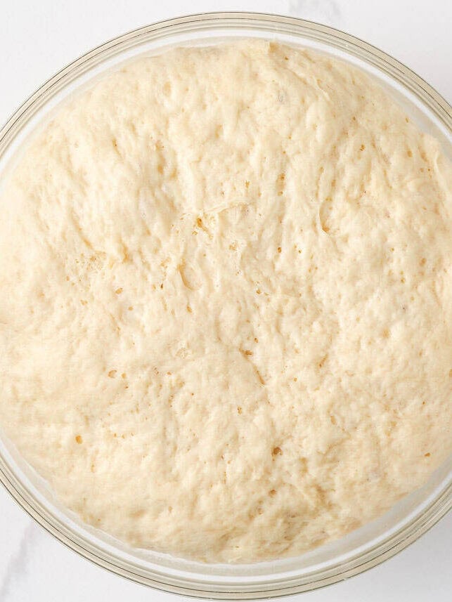 Warm, gooey, and dripping in a maple caramel glaze and pecan topping, these homemade sticky buns are the perfect bake for your next holiday brunch or cozy weekend morning! Sticky bun dough after first rise, doubled in size and fluffy inside a glass bowl.