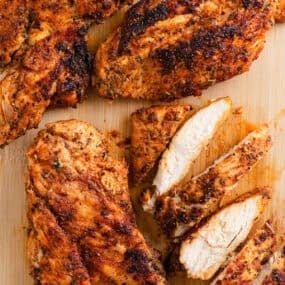 Vertical image of sliced blackened chicken showing the crisp seasoning crust and moist white meat inside.