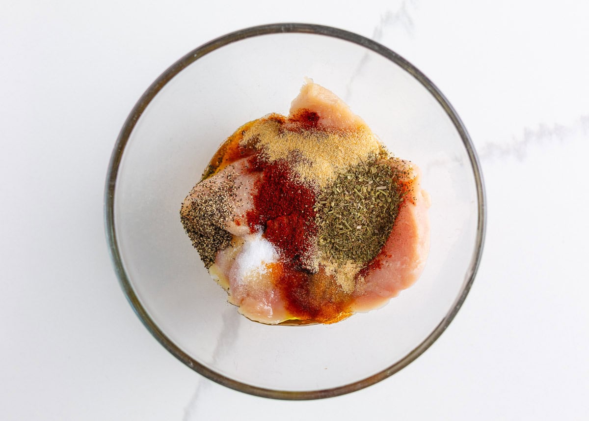 Make perfectly seasoned blackened chicken with a smoky crust and tender, juicy middle. Serve it over creamy Alfredo, rice, or salad for an easy way to add big flavor to any dinner. Raw chicken breasts in a glass bowl topped with olive oil, smoked paprika, garlic powder, Italian seasoning, and other blackened seasoning spices.