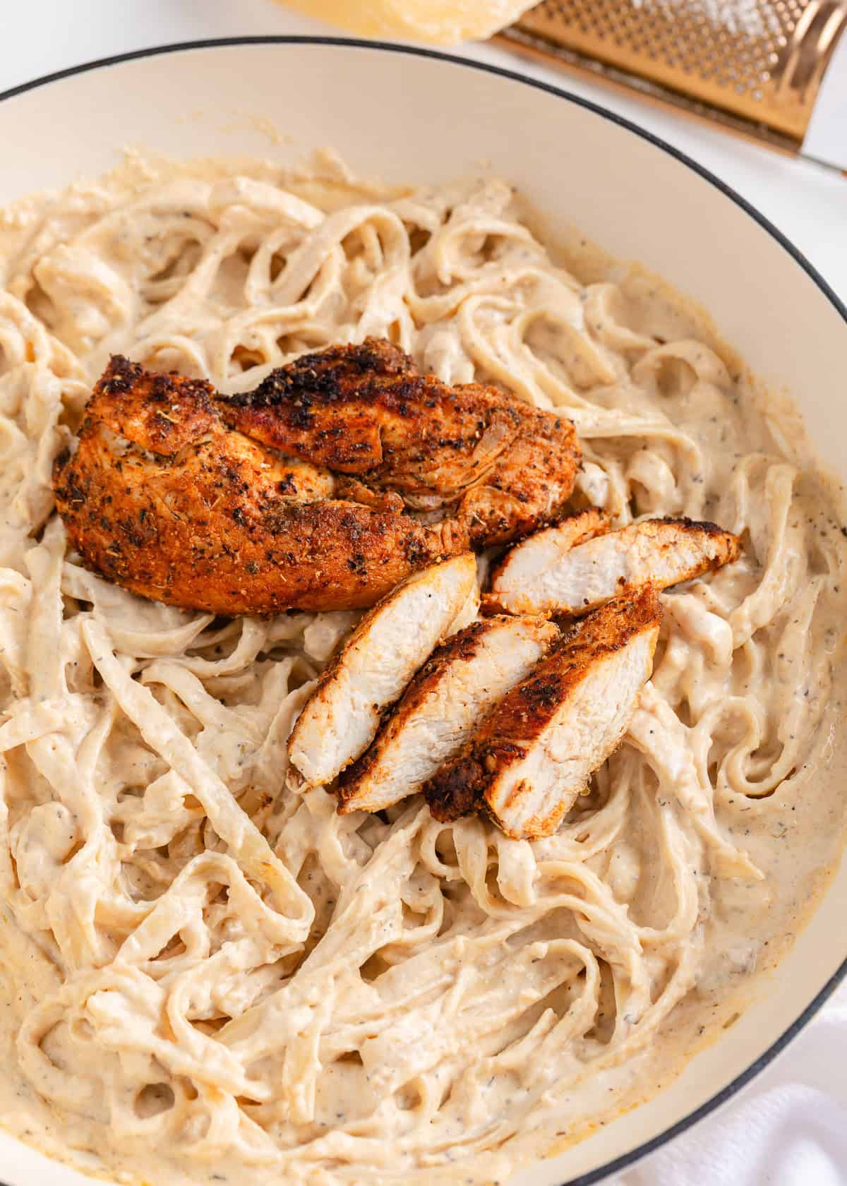 Make perfectly seasoned blackened chicken with a smoky crust and tender, juicy middle. Serve it over creamy Alfredo, rice, or salad for an easy way to add big flavor to any dinner. Juicy sliced blackened chicken served over creamy fettuccine Alfredo in a large skillet.