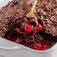 Freshly baked chocolate cherry dump cake with gooey cherry filling and melted chocolate chips being served.