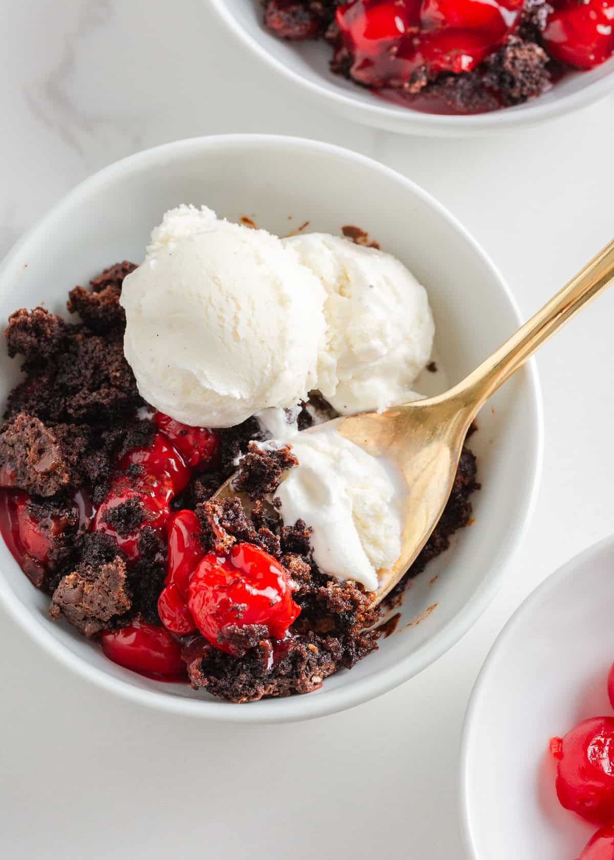 Rich, gooey, and packed with chocolate cherry flavor, this chocolate cherry dump cake is made with only 4 ingredients and minimal prep. It's a quick and easy indulgent dessert! Warm chocolate cherry dump cake served with scoops of vanilla ice cream in a white bowl.