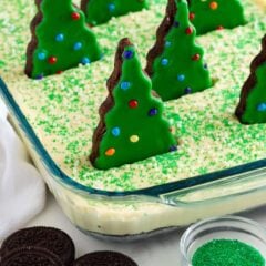 Close-up of creamy Christmas dirt cake with Oreo cookie crust, green sprinkles, and Christmas tree brownies decorated with colorful candy pieces.