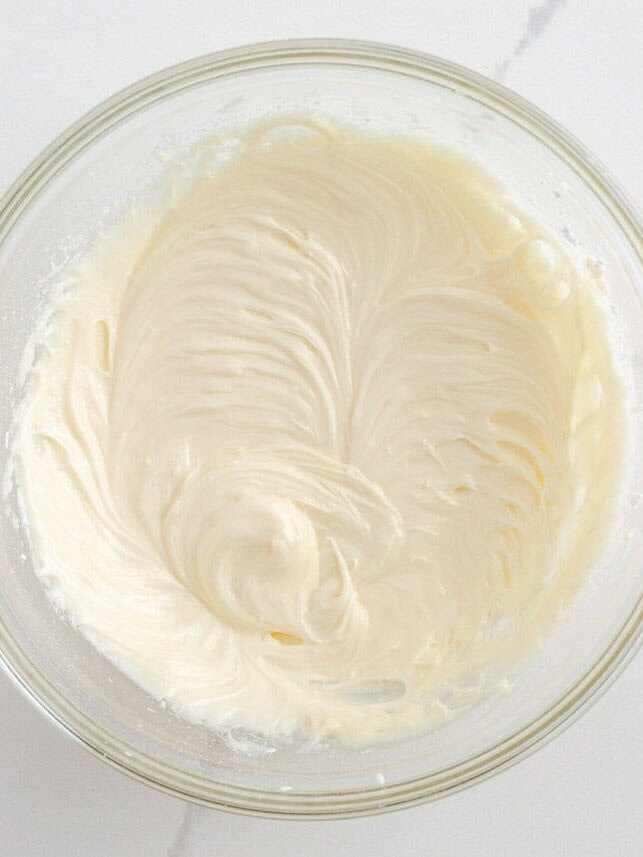 Bowl of fluffy cream cheese frosting ready for Christmas sugar cookie bars.