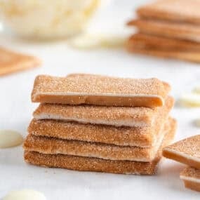 Churro toffee square broken in half revealing smooth caramel center and cinnamon sugar coating.