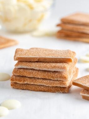 Churro toffee square broken in half revealing smooth caramel center and cinnamon sugar coating.