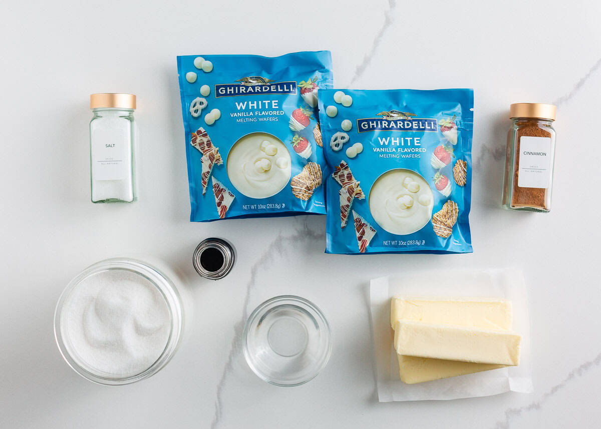 Bring home a taste of Disneyland with this churro toffee recipe. Buttery toffee coated in white chocolate and dusted with cinnamon sugar has classic churro flavor in every bite. Ingredients for churro toffee including butter, sugar, cinnamon, vanilla, and white chocolate melting wafers laid out on a countertop.