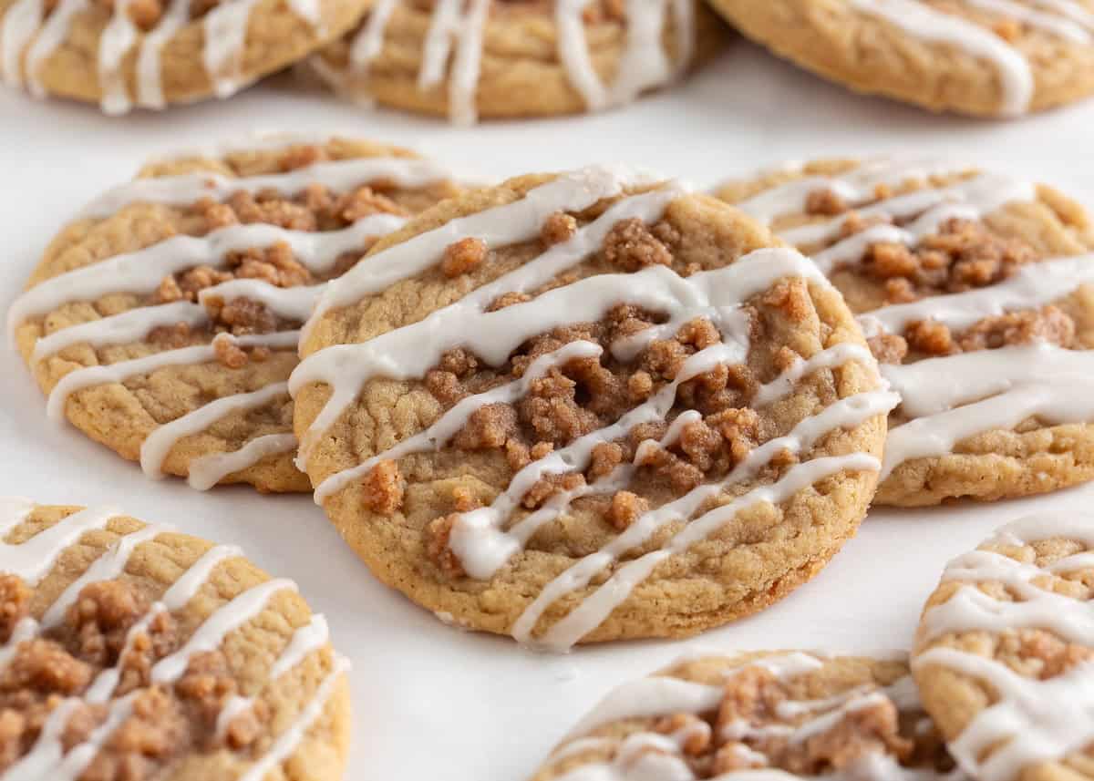 Originally inspired by The Gilmore Girls, these coffee cake cookies are made with a soft and chewy cinnamon-infused brown sugar cookie with a crumb topping and vanilla glaze! Close-up of a soft coffee cake cookie topped with cinnamon crumb and sweet glaze drizzle.