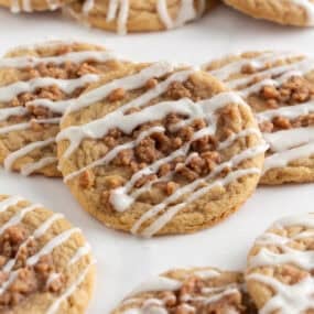 Soft and chewy coffee cake cookies arranged on parchment, topped with cinnamon streusel and glaze.