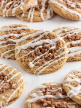 Soft and chewy coffee cake cookies arranged on parchment, topped with cinnamon streusel and glaze.