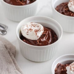Creamy homemade chocolate pudding in a ramekin topped with a dollop of whipped cream and chocolate shavings.