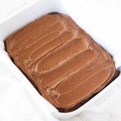 Pan of brownies covered with smooth chocolate brownie frosting that is swirled across the top.