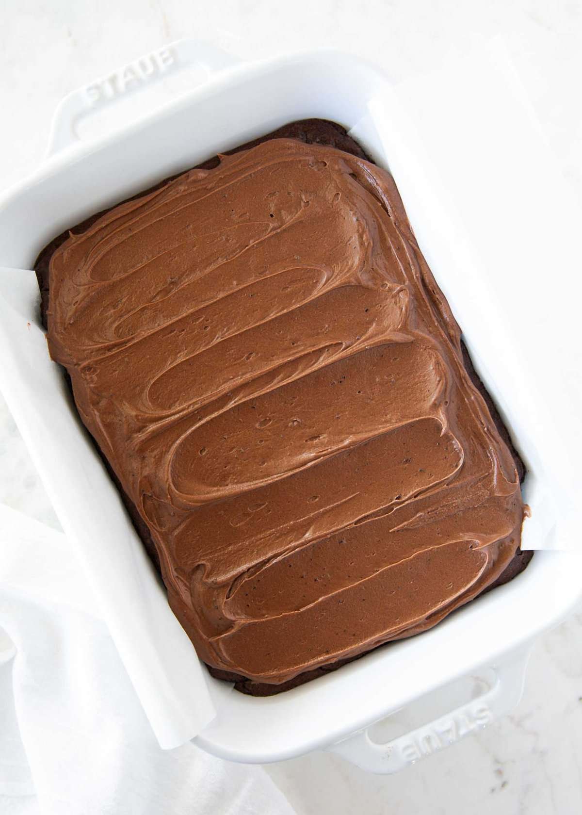 This thick and creamy brownie frosting sets up perfectly and brings a nostalgic, rich chocolate flavor to homemade or boxed brownies. Frosting for brownies spread across a pan of cooled brownies.