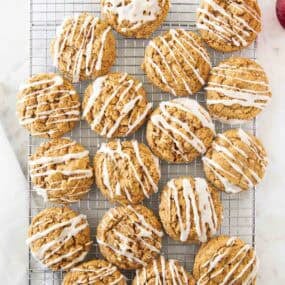 Gingerbread oatmeal cookies cooling on a wire rack with vanilla glaze drizzled on top.