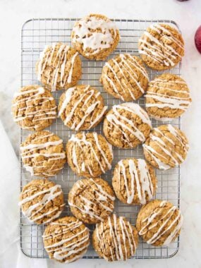 Gingerbread oatmeal cookies cooling on a wire rack with vanilla glaze drizzled on top.
