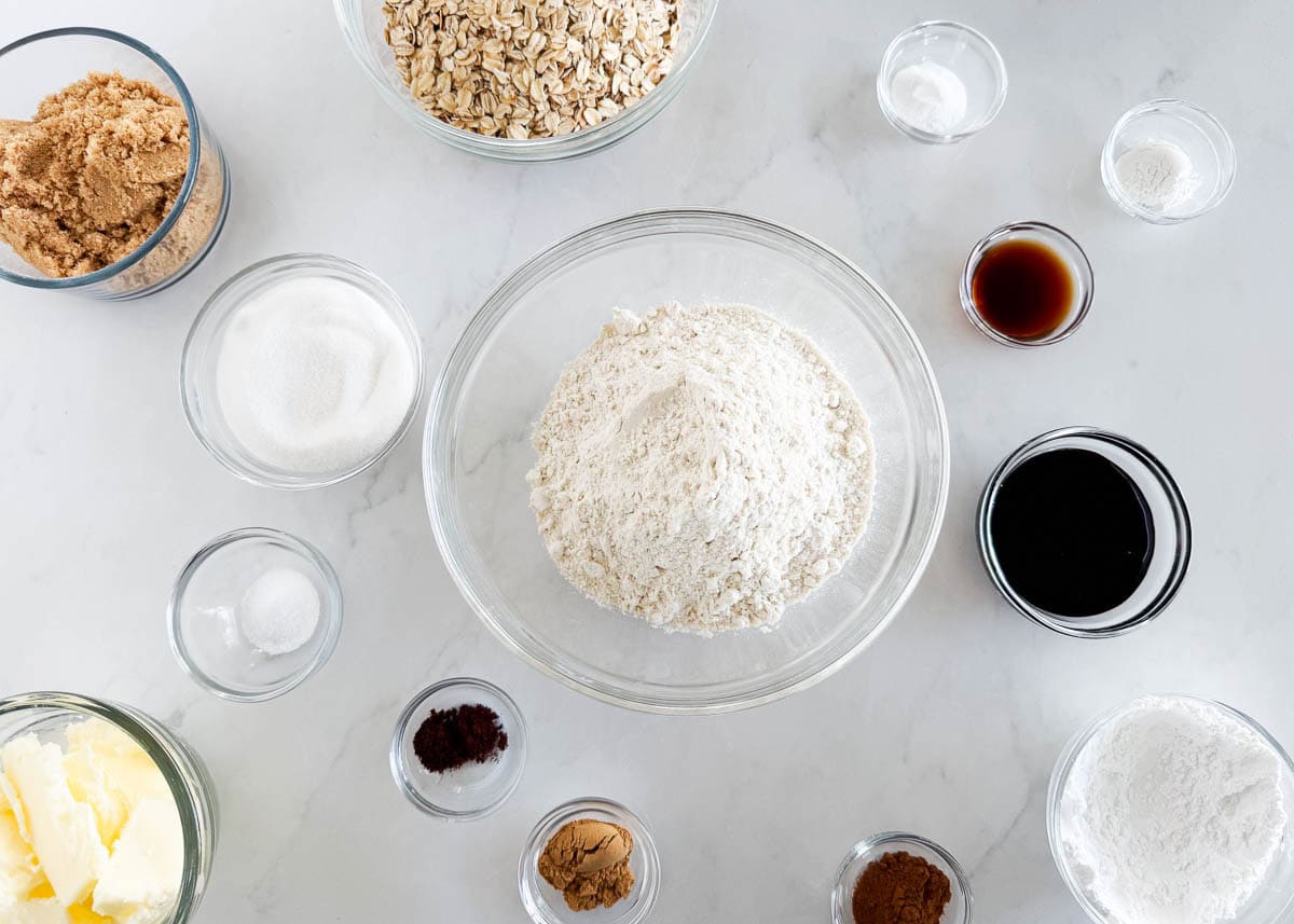 Overhead view of the ingredients needed to make gingerbread oatmeal cookies, including oats, flour, sugars, spices, and molasses.