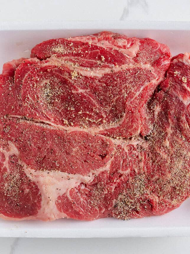 Raw beef chuck roast seasoned with salt, pepper, garlic powder, and onion powder before browning for Instant Pot pot roast.