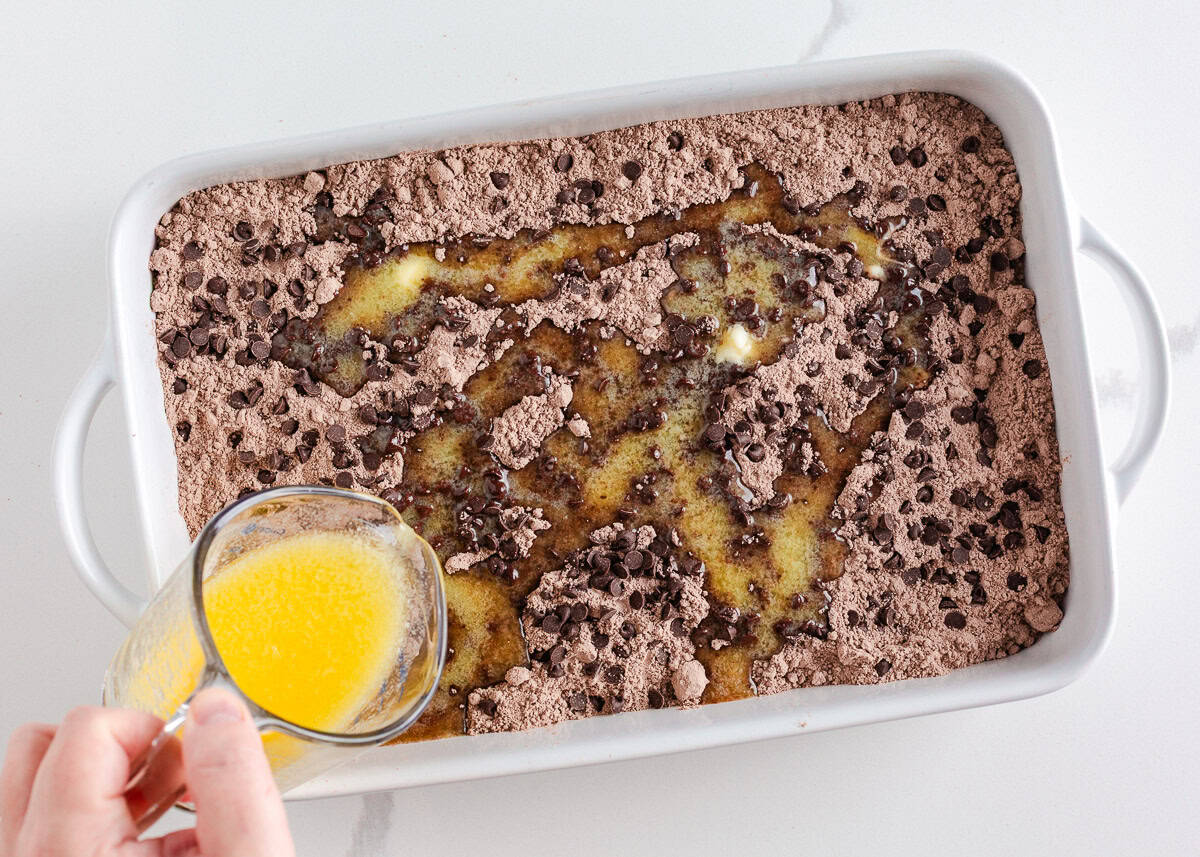 Rich, gooey, and packed with chocolate cherry flavor, this chocolate cherry dump cake is made with only 4 ingredients and minimal prep. It's a quick and easy indulgent dessert! Pouring melted butter over dry chocolate cake mix and chocolate chips to make chocolate cherry dump cake.