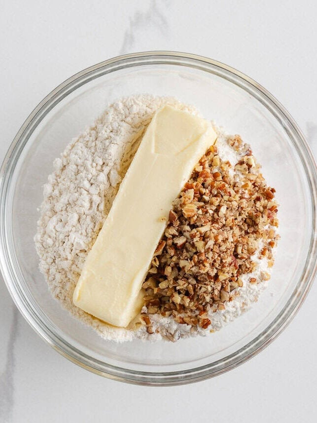 Bowl of flour, chopped pecans, and a stick of butter ready to mix for the pecan shortbread crust.
