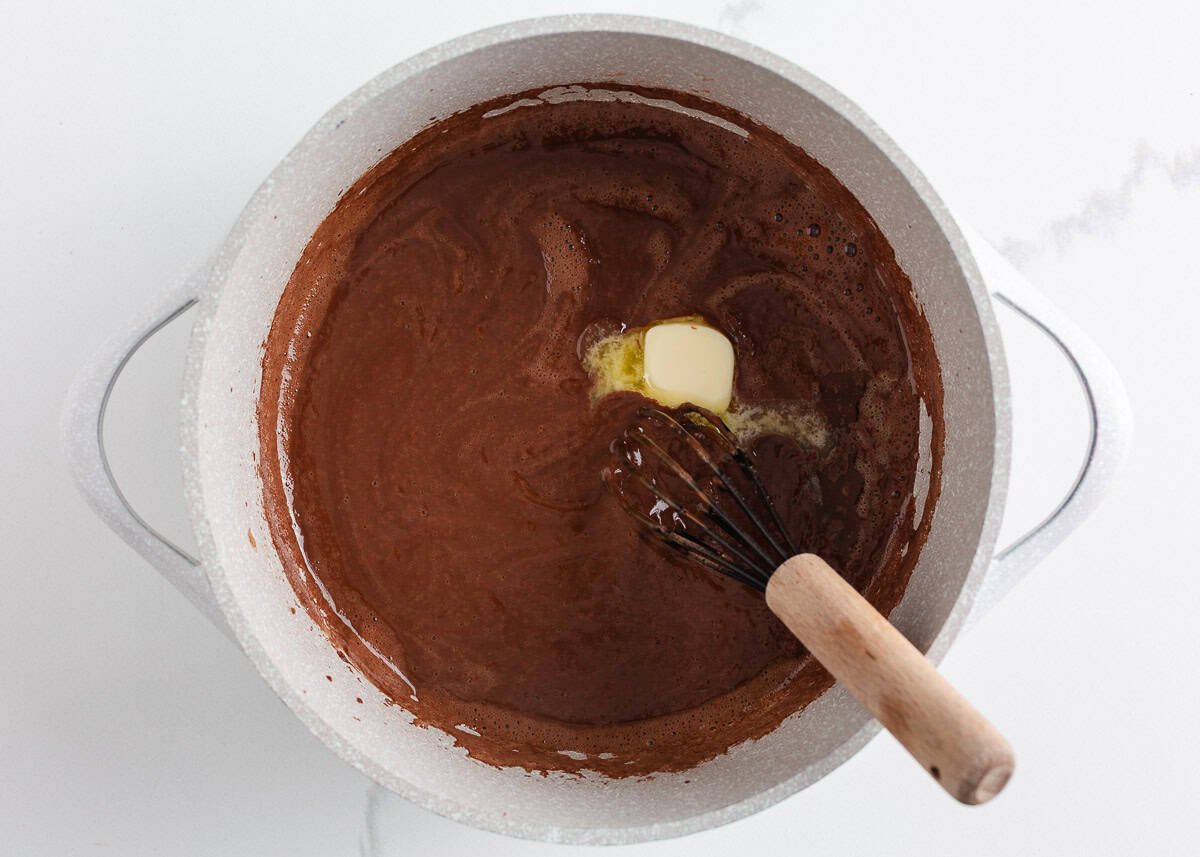 This homemade chocolate pudding is rich, creamy, and easy to make from scratch with just a few simple ingredients. It's just the treat when a chocolate craving hits! Homemade chocolate pudding mixture simmering in a saucepan with a pat of butter melting in.