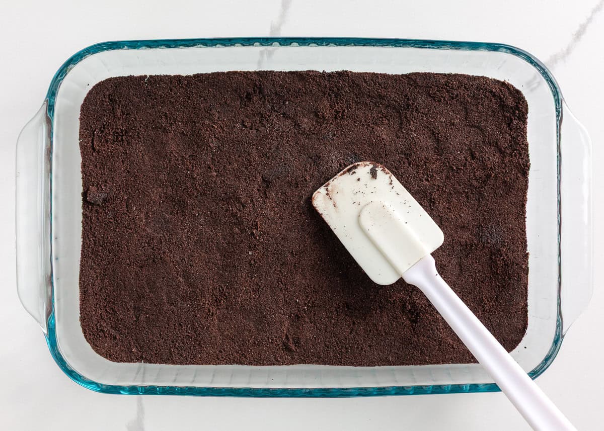 This Christmas dirt cake is a simple, no-bake dessert made with an Oreo crust, creamy whipped topping pudding layer and decorated with Little Debbie Christmas trees! Crushed Oreo crumbs pressed into the bottom of a glass 9x13 baking dish using a rubber spatula to form the crust.