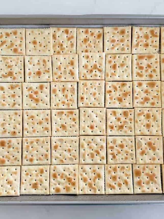 Saltine crackers lined up in a single layer on a baking sheet for churro toffee.