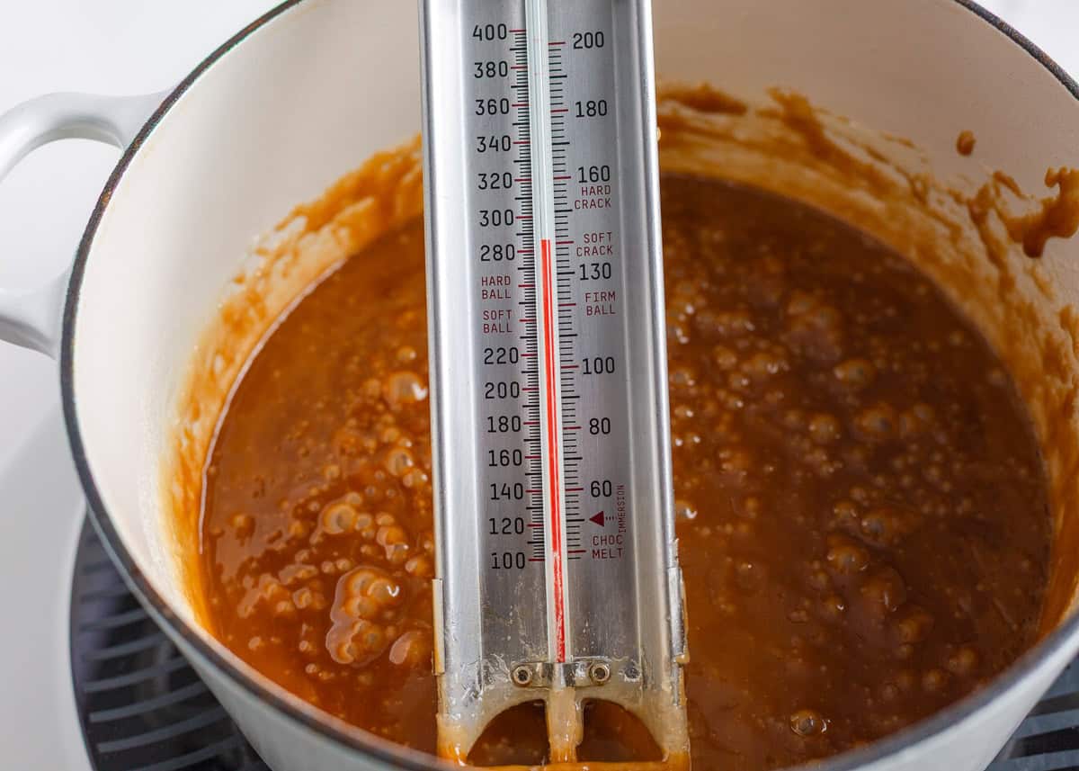 Bring home a taste of Disneyland with this churro toffee recipe. Buttery toffee coated in white chocolate and dusted with cinnamon sugar has classic churro flavor in every bite. Candy thermometer clipped to a pot of bubbling caramel while cooking churro toffee to temperature.