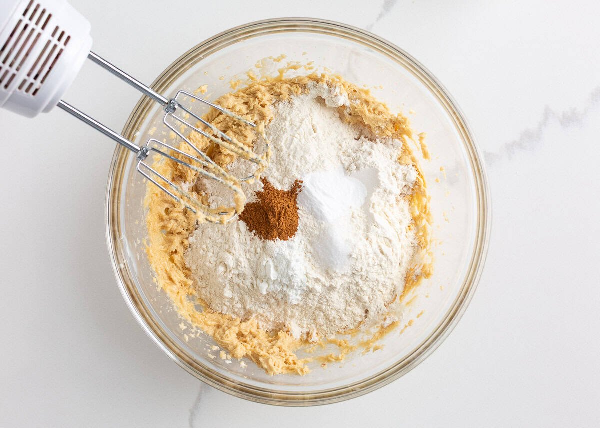 Originally inspired by The Gilmore Girls, these coffee cake cookies are made with a soft and chewy cinnamon-infused brown sugar cookie with a crumb topping and vanilla glaze! Flour, cinnamon, baking soda, and cornstarch added to creamed butter and sugar while mixing cookie dough.