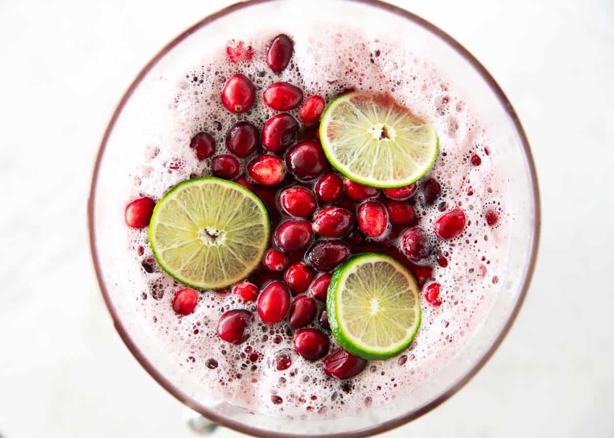 This easy cranberry punch is fizzy, festive, and perfect for holiday gatherings. Just mix juices, add fruit on top, and you’ve got a crowd-pleasing Christmas drink everyone loves. Overhead view of a festive cranberry punch topped with fresh cranberries and lime slices, with light bubbles around the edges.