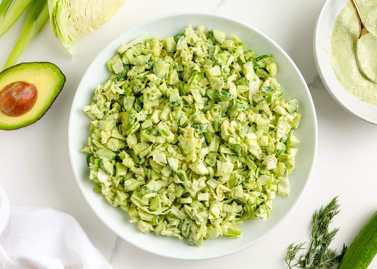 Learn to make this TikTok Green Goddess Salad with the best, most flavorful homemade green goddess salad dressing you're going to want to put on everything! Bowl of green goddess salad mixed with creamy herb dressing and chopped vegetables
