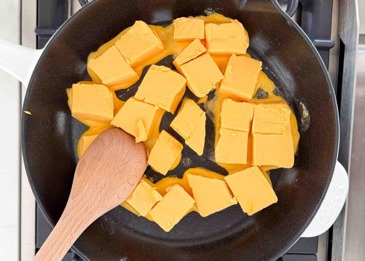 Cubes of processed cheese melting in a skillet as the first step in making Chili’s skillet queso copycat recipe.