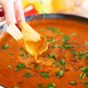Tortilla chip dipped into smooth and creamy Chili&rsquo;s skillet queso in a skillet for a homemade copycat version.