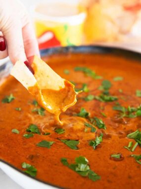 Tortilla chip dipped into smooth and creamy Chili&rsquo;s skillet queso in a skillet for a homemade copycat version.