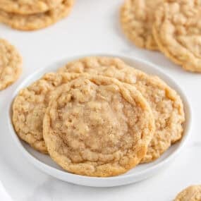 Close-up of soft homemade oatmeal cookies on a white plate, showing their chewy centers and crisp edges.